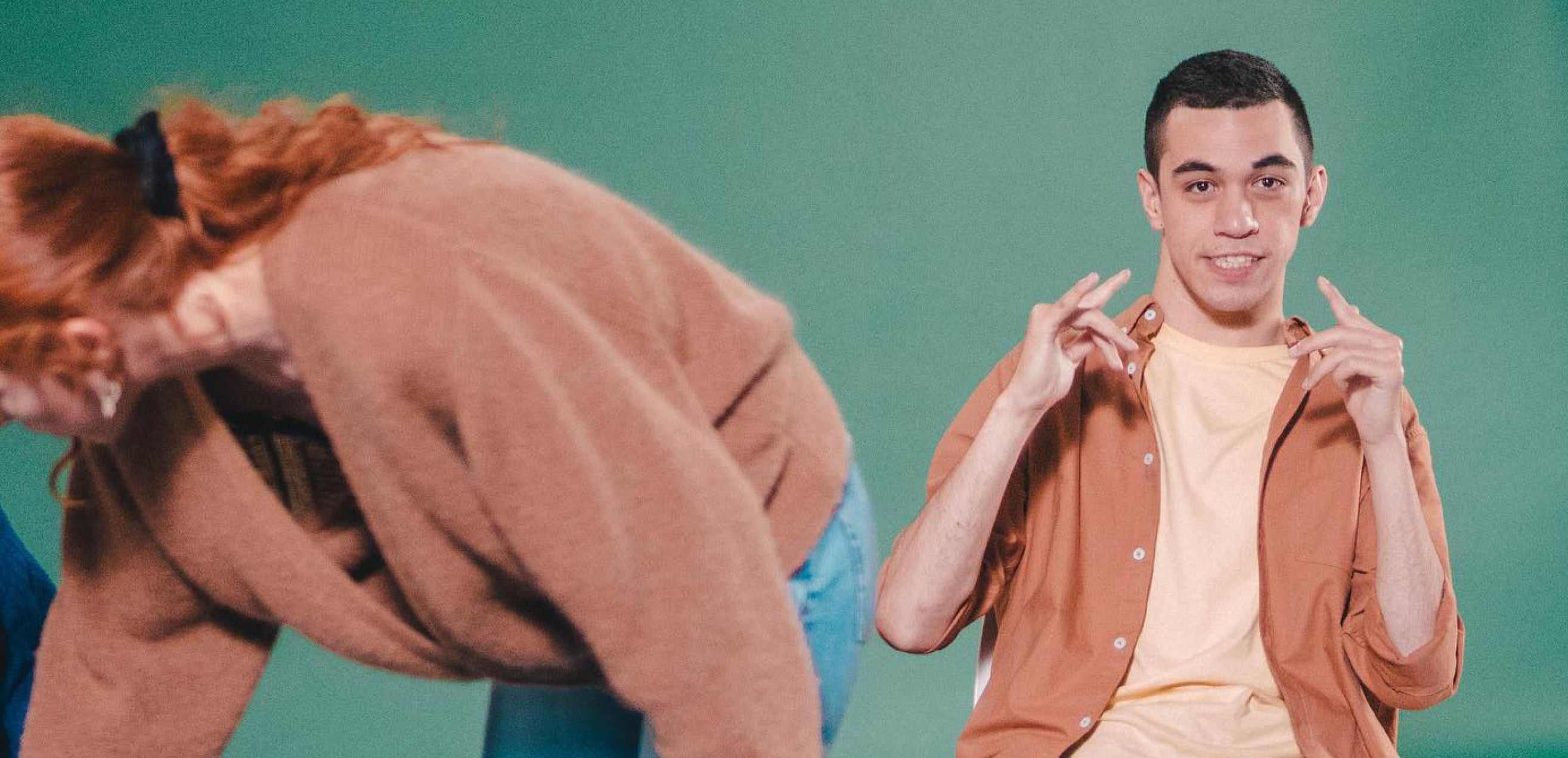 William, a young NZ man is posing whilst sitting on a chair at a photoshoot set.